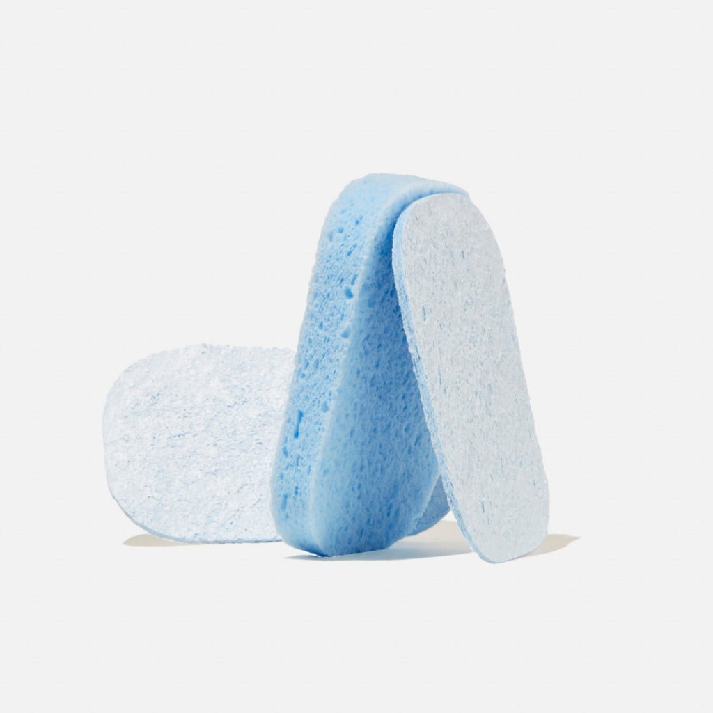 Three blue, rectangular cleaning tablets with rounded edges are standing and lying next to each other on a white background.