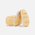 Three natural loofah sponges with rounded edges are stacked on a white background. One sponge has a visible fabric label, and another has a light blue trim along the side.