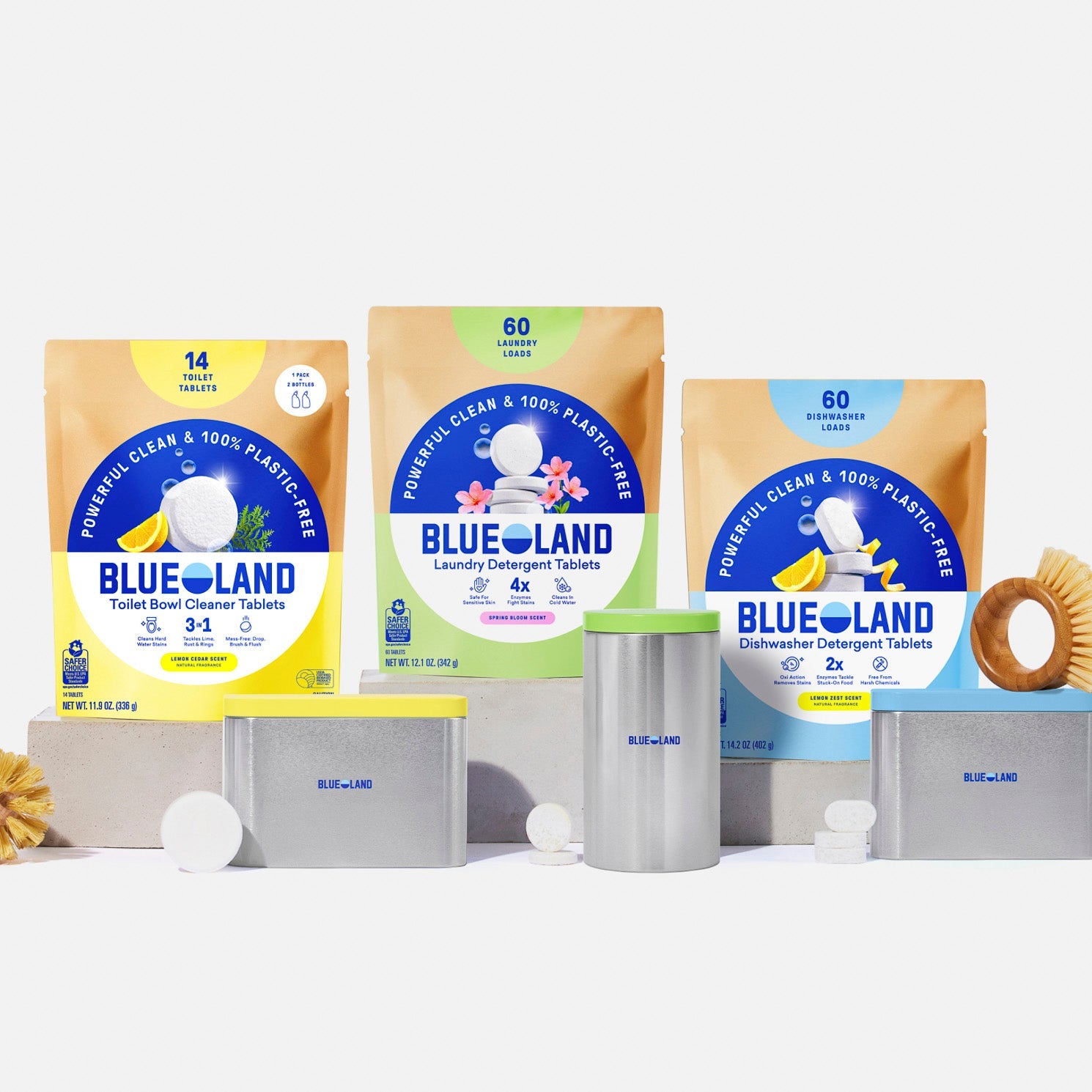 The Tablet Trio Kit is displayed with metal storage tins and brushes, featuring BlueLand's plastic-free Toilet Bowl Cleaner, Laundry Detergent, and Dishwasher Detergent Tablets against a white background.