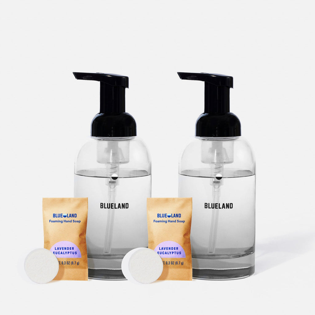 The BLUELAND Hand Soap Starter 2-Pack includes two clear reusable glass dispensers with black pumps, each with a Foaming Hand Soap Lavender Eucalyptus packet and plastic-free tablets, all shown on a plain white background.