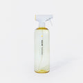 A clear, yellow-tinted spray bottle with a white and yellow nozzle, labeled “BUGLAND Multi Surface” in black text, standing upright against a plain white background.